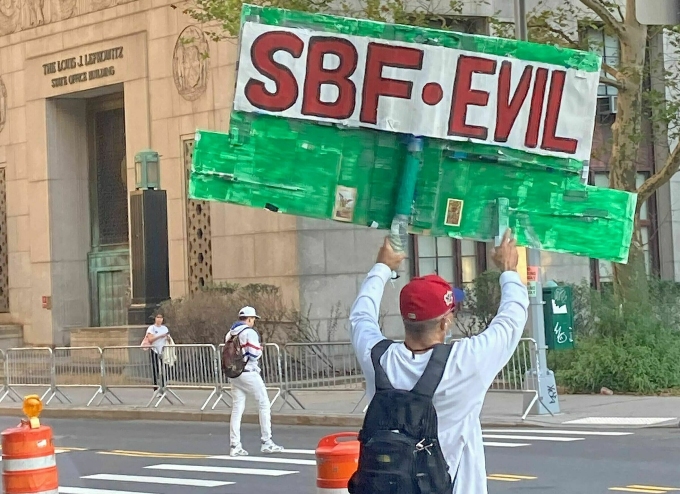 Một người cầm tấm bảng với nội dung SBF độc ác đứng ngoài tòa sán xét xử Sam Bankman-Fried ở New York, Mỹ. Nguồn: Cointelegraph